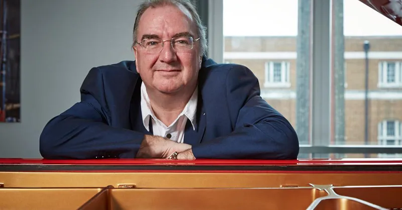 Silent Cinema Maestro Neil Brand leaning on top of a paino